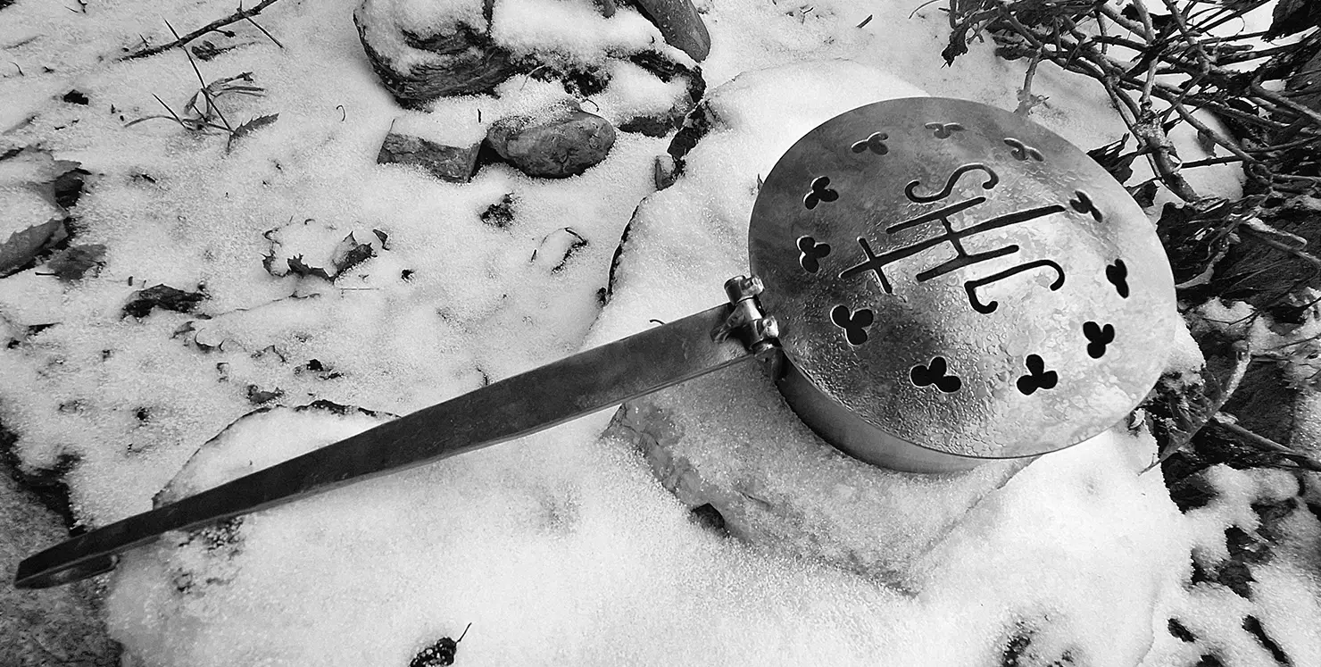 Gusseiserne Räucherpfanne für Schmanaisches Räuchern auf einnem schneebedeckten Stein